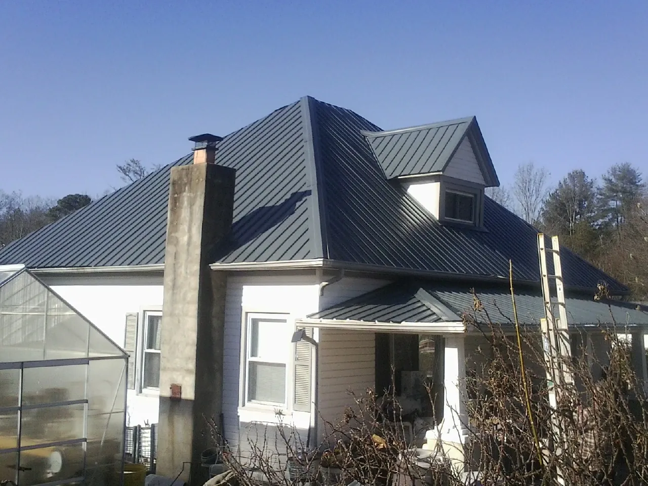 Dark blue standing seam metal roof on a white farmhouse with dormer — Slate & Tile Roof Repair by Roofing Brothers in North Weymouth