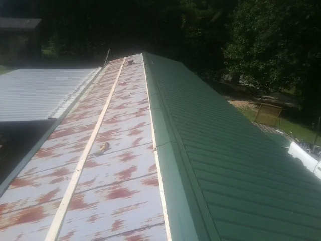 Old rusted panels beside newly installed green metal roofing — Wind Damage Roof Repair by Roofing Brothers in North Weymouth