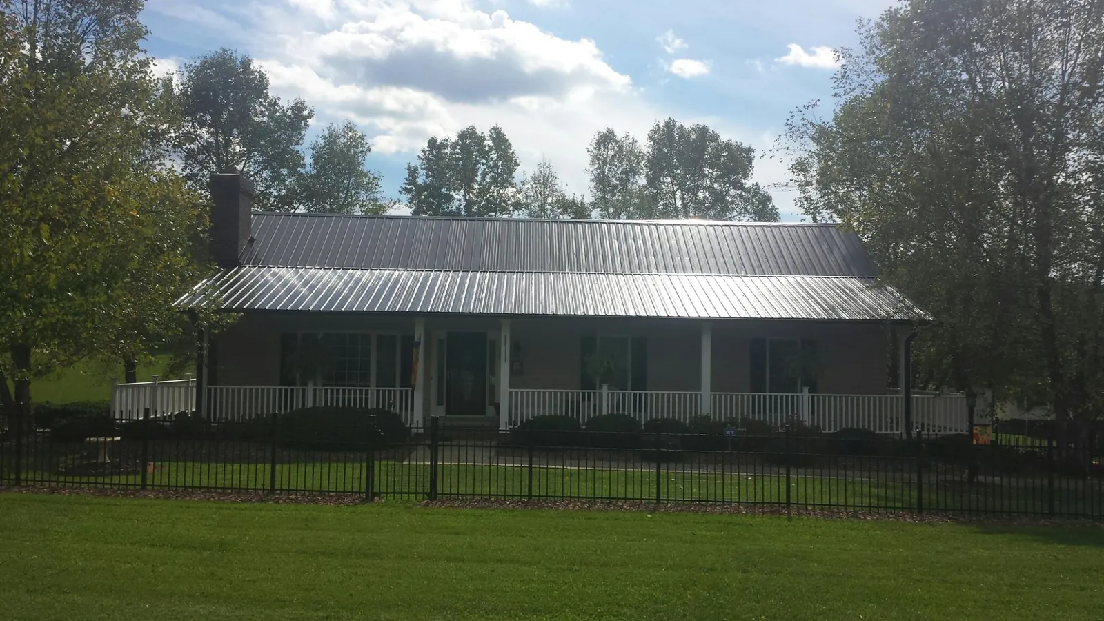 Gray metal roof on a brick ranch with a full width front porch — Gutter Guard Installation work by our crew in North Weymouth