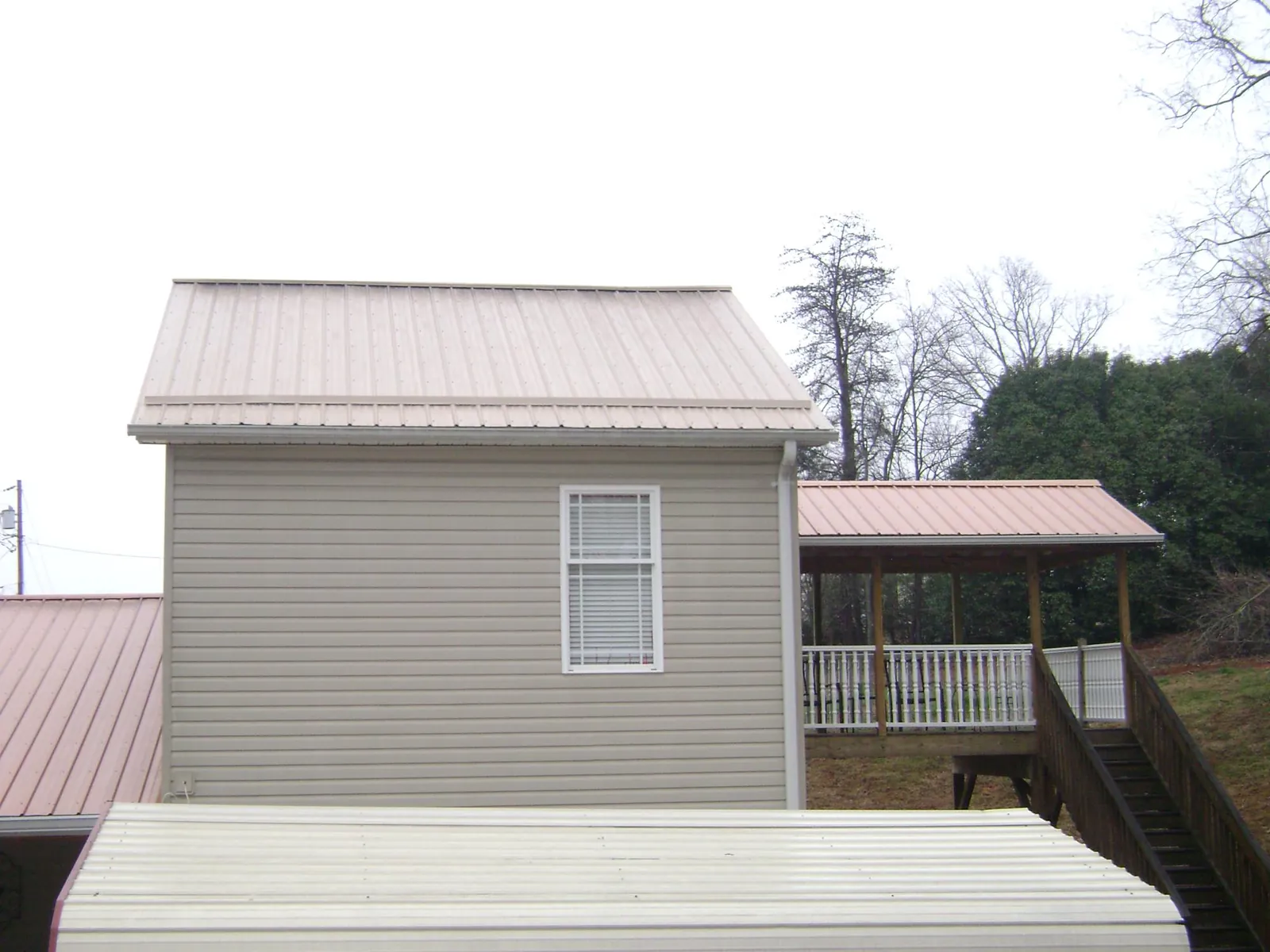Tan metal roofs on a two story addition and attached porch, from a Roof Replacement job in North Weymouth