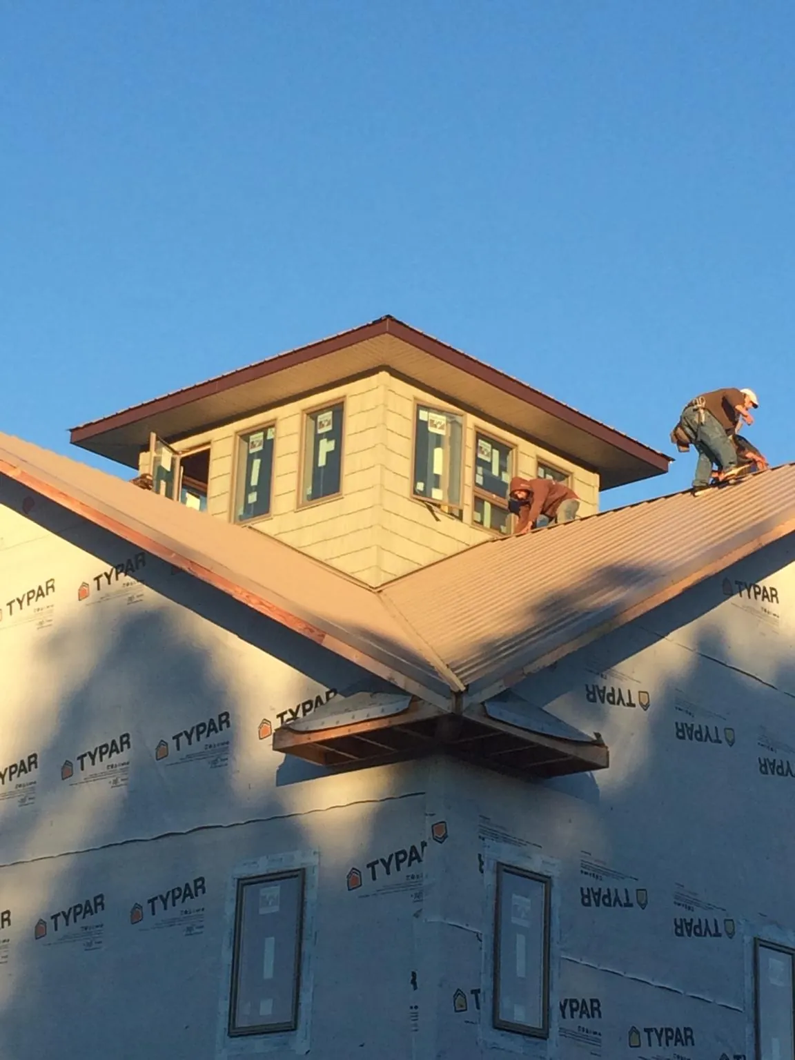 Roofers working around a rooftop cupola on a new metal roof at sunset — Roof Waterproofing in North Weymouth by Roofing Brothers